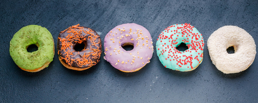 Donuts with a colorful icing on a dark background. Web Food Banner