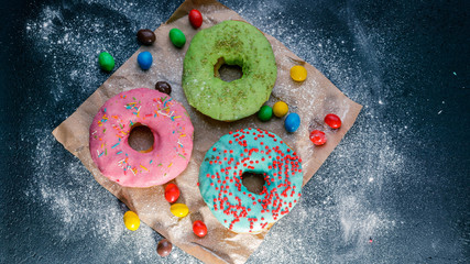 Donuts with a colorful icing on a dark background. Top view