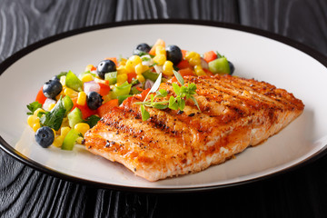 Healthy food: grilled salmon fillet with pepper, corn, blueberry and onion salad closeup on a plate on the table. horizontal