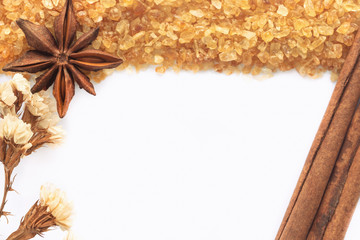 Natural brown sugar or no bleach sugar and cinnamon stick and anise on white isolated background with copy space in top view flat lay. Sweet seasoning and spice for good health of cooking or bakery.