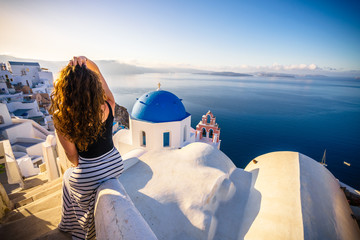 Girl in white dress looking at blue domes in Santorini, Greece