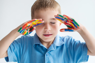 Little boy closed eyes and shows colored painted hands. Meditation. Imagination