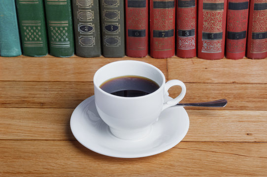Hot cup of fresh coffee on the wooden table  with books