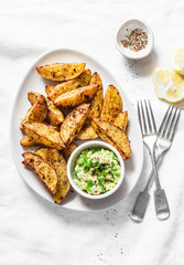 Roasted spices potato with avocado salsa on light background, top view. Tasty snack, tapas or appetizers. Vegetarian food concept