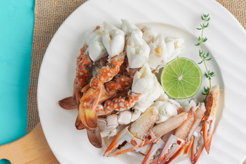 Steamed crab meat prepared for ready to eat with lime or lemon and thyme on white plate blue table in top view flat lay with copy space for background or wallpaper. Delicious homemade seafood concept.