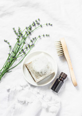 Homemade lavender soap, lavender flowers, face brush, essentials oil  on light background, top...