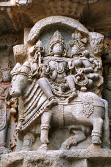 Fototapeta na wymiar Ornate wall panel reliefs depicting Shiva-Parvati seated on Nandi, Kedareshwara temple, Halebidu, Karnataka