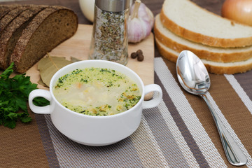 Mushroom soup with croutons in a white dish is on a wooden table.