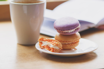 French colored macarons on the plate and a cup of coffee