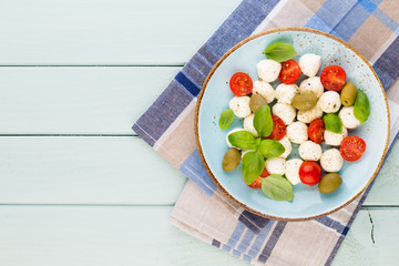 Delicious caprese salad with ripe cherry tomatoes and mini mozzarella cheese balls with fresh basil leaves.
