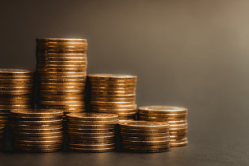Savings, increasing columns of coins, piles of coins arranged as a graph in dark room, business banking concept.