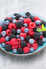 Fresh berry salad on blue dishes. Vintage wooden background.