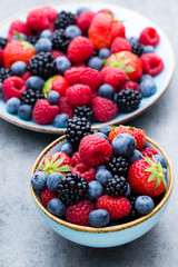 Fresh berry salad on blue dishes. Vintage wooden background.