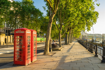 A traditional red phone booth in London at sunny morning