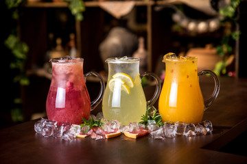 Delicious set of refreshing summer drinks on wooden background with ice pieces