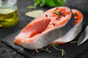 Salmon. Raw trout fish steak with herbs on black slate background. Cooking, seafood. Healthy eating concept