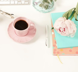 Flat lay women's office desk. Female workspace with laptop,  flowers peonies,  accessories, notebook, glasses, cup of coffee on white background. Top view feminine background.Copy space