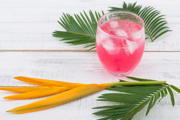Watermelon fresh drink decorate with fern leaves and bird of paradise on white wood background, selective focus on watermelon drink and ice