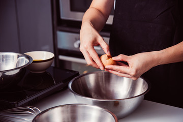 Fototapeta na wymiar Woman girl baker in kitchen cooking whisk egg to bowl