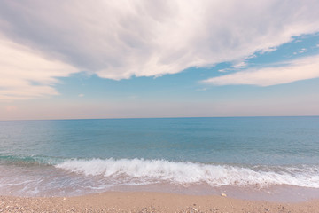 Idyllic seascape with surf line and beautiful clouds over sea. Sea view from tropical sand beach with sunny sky. Summer paradise beach.