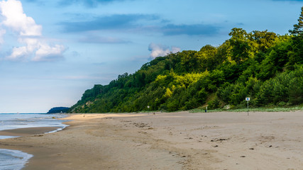 Strand mit grünen Hügeln und blauem Himmel im Hintergrund an der Ostsee Querformat - obrazy, fototapety, plakaty