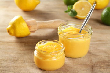 Lemon cream in a jar and a juicer on a wooden table