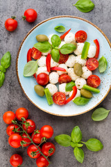 Delicious caprese salad with ripe cherry tomatoes and mini mozzarella cheese balls with fresh basil leaves.