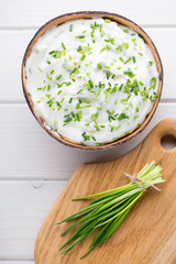 Bowl of cream cheese with green onions, dip sauce on wooden table.