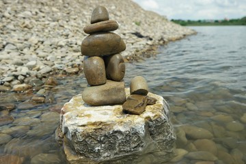 Fototapeta na wymiar Rock balancing against the background of the river and sky