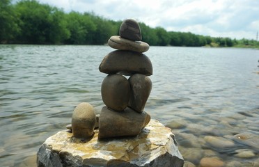 Rock balancing against the background of the river and sky