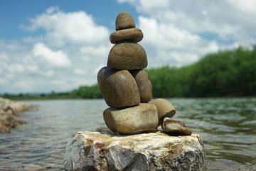 Rock balancing against the background of the river and sky