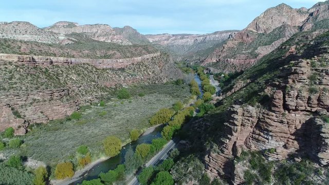 Aerial drone scene of Atuel river canyon in San Rafael, Mendoza, Cuyo Argentina. Camera moving forwards. Street next to the willows trees and river. Colorful rocks.