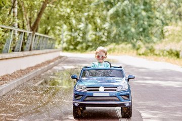 The girl is having fun riding a blue electric car in the park. Toning.