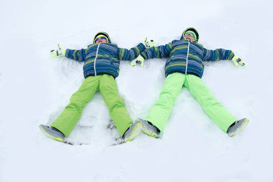 Happy boys in colorful winter clothes doing gymnastics on ice and snow. Glasses for skiing, snowboarding and sledging. A child is playing outdoors in the snow. Outdoor fun for winter holidays