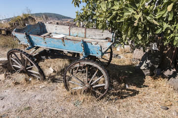 Fototapeta na wymiar An old and disused blue carriage in a village in Cunda, Ayvalik, Turkey