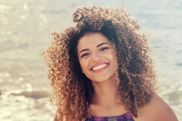 Pretty woman portrait smiling widely near the sea on Summer vacations