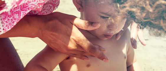 Mom applying solar protecting cream on her little daughter's face, letterbox