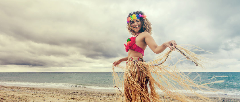 Happy and cheerful hawaiian woman portrait dancing on the beach, letterbox