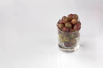 Red gooseberry in a clear glass on a light background