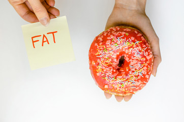 Woman hand holding pink donut with sprinkles extra calories fat fast food excess weight unhealthy...