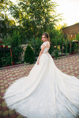 Fototapeta premium Young girl in wedding dress in park posing for photographer