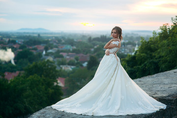 Teenage girl in wedding dress on city. Background town sunset