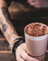 A girls hand holding out a hot chocolate