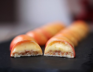 Cut of white chocolate bonbons with mango and pasiion fruit on a black board