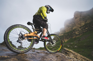 Extreme mountain bike sports athlete man in helmet riding outdoors against a background of rocks....