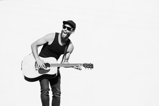 Guitar player singing outside. Hipster guitar player with beard and black clothes