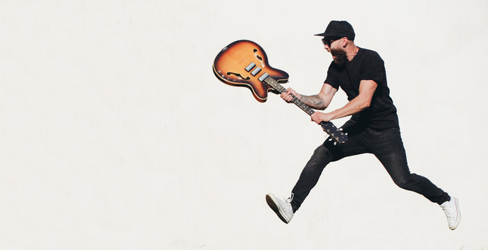 Guitar player singing outside. Hipster guitar player with beard and black clothes