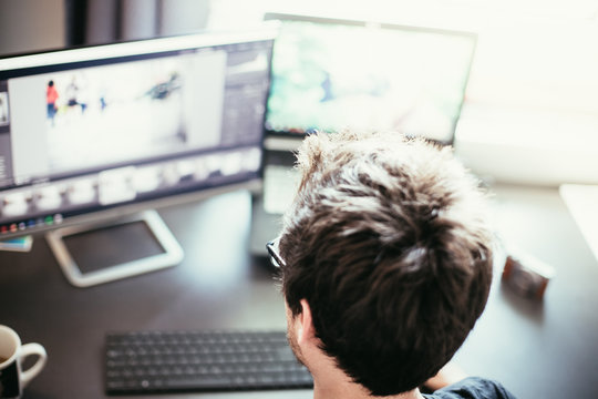 Junger Mann arbeitet an PC, Home-Office, Aufnahme von hinten