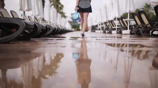beautiful girl in clothes and with a backpack walking near the pool