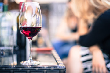 Weinglas mit Rotwein, Gartenparty, Gastgarten in der Abendsonne, Textfreiraum